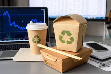 Eco-friendly paper packaging for food delivery. Disposable tableware with a recycling sign in the office.