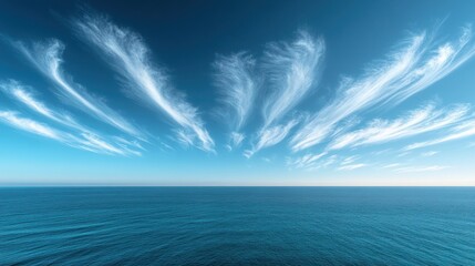 A vast expanse of blue ocean stretches out to meet the horizon, beneath a sky filled with wispy, white cirrus clouds.