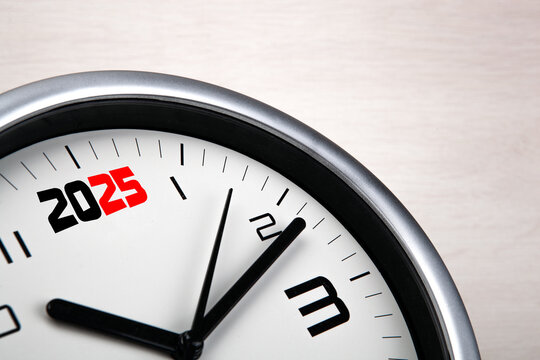 large white clock face with digits on a wooden background closeup