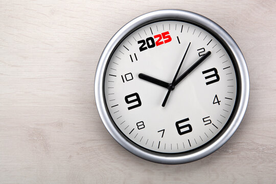 large white clock face with digits on a wooden background closeup