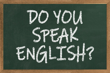 A chalkboard with the text do you speak english? written in it, a pot with pencils and the flag of the United Kingdom, on a wooden desk, with green background