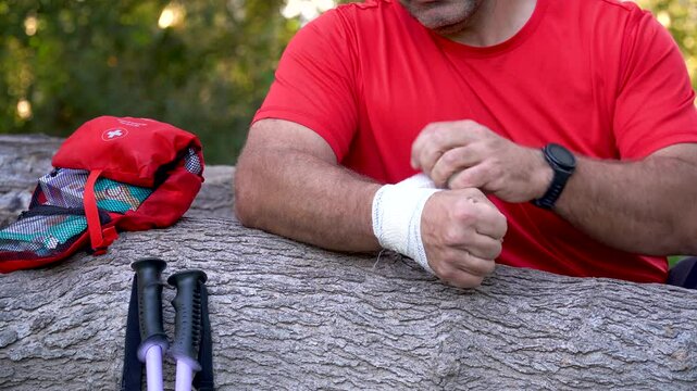 A hiker bandages his injured wrist next to a first aid kit. Real time video