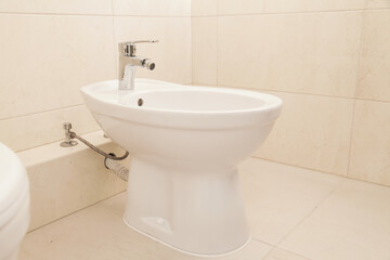 White Bidet in bathroom, beige tiled. Quiet Luxury