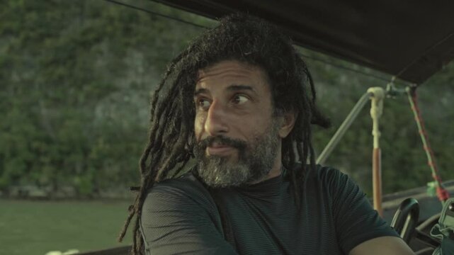 bearded rastaman sitting on a boat sailing dreads locks hair style hippie free