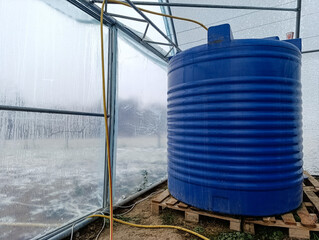 A large blue water tank sitting inside of a greenhouse