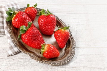 Bowl with strawberries on white wooden table.