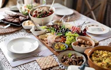 Fresh food for eating on a table for lunch or breakfast. Cold plate of various salad, cheese, ham, grapes and olives on board. Homemade meal prepared at home with napkin . Banner.