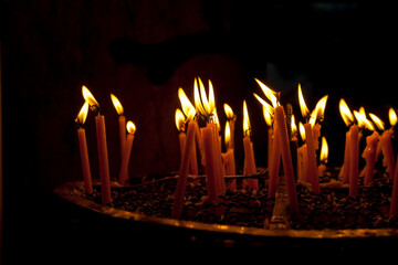 Candles burning brightly in a dimly lit religious setting at night
