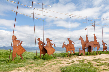 Metal sculptures of pilgrims on Alto del Perdon on the Camino de Santiago surrounded by scenic...