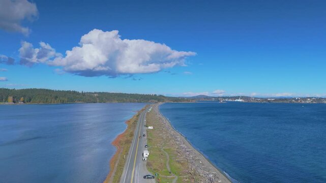 Drone perspective of Ocean Boulevard adjacent to Esquimalt Lagoon, featuring a serene stretch of road lined with scattered vehicles in Victoria Canada