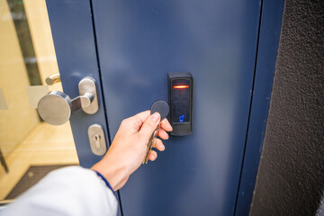 Close up view of person using a electric lock key fob to access a building via a reader of entry...