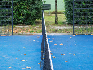 outdoor padel court with a blue surface, equipped with net floodlights and glass © manola72