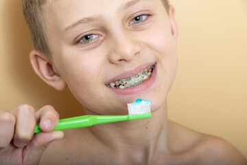 A 10-year-old teenager in dental braces is brushing his teeth. the concept of healthy teeth and proper dental care