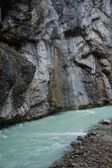 Waterfall Draining into a River Surrounded by Rocky Cliffs in a Swiss Gorge