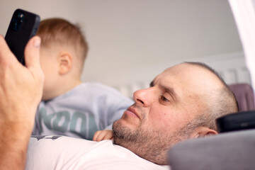  A young grandfather and a small grandson look enthusiastically at the phone in their free time...