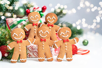 Four gingerbread men are smiling and holding hands