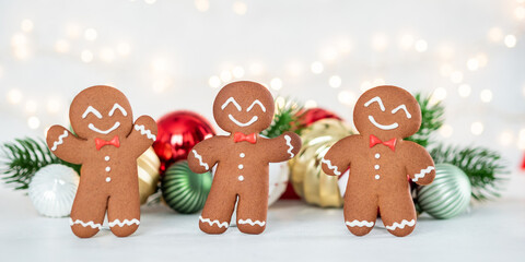 Three gingerbread men are standing next to each other with a bow tie and smiling
