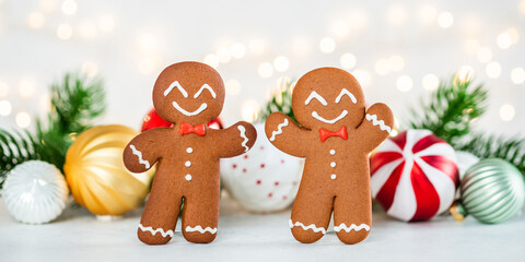 Two gingerbread men are smiling and standing next to each other