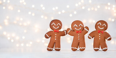 Three gingerbread men are smiling and waving at the camera