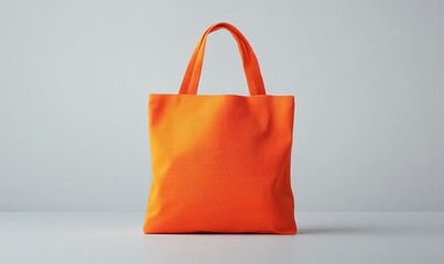 A vibrant orange tote bag lying on a white surface, ideal for showcasing logos, text, or design ideas