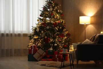 Christmas tree with festive decor, presents, coffee table and armchair in cozy room