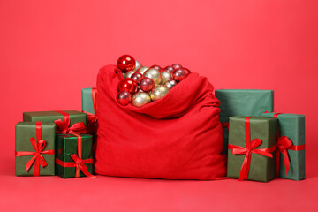 Santa Claus bag with baubles and gift boxes on red background