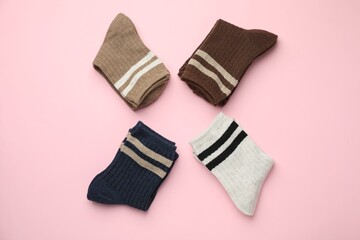 Different comfortable socks on light pink background, flat lay