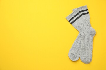 Pair of soft comfortable socks on yellow background, top view. Space for text