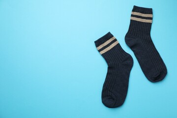 Pair of soft comfortable socks on light blue background, top view. Space for text