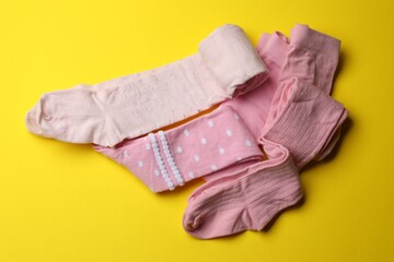 Pink child's tights on yellow background, flat lay