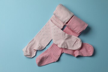 Pink child's tights on light blue background, top view