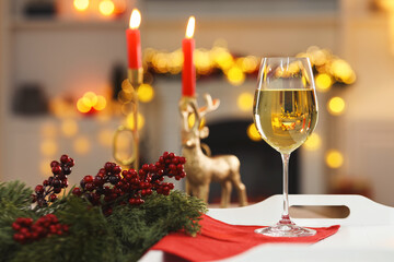 White wine in glass and Christmas decor on tray against blurred lights, bokeh effect
