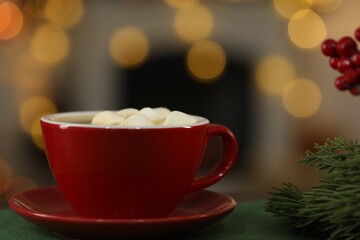 Tasty cocoa with marshmallows in cup and decor on table against blurred Christmas lights, closeup. Bokeh effect