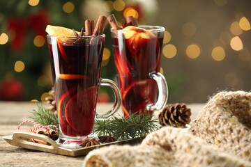 Tasty mulled wine with spices and decor on wooden table against blurred Christmas lights, bokeh...