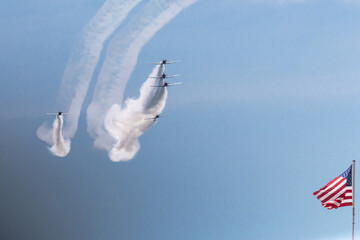 Pilots Perform Aerial Maneuvers With Smoke Trails Near American Flag on a Clear Sunny Day