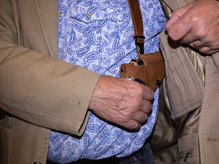 A man reaches for a pistol in his shoulder holster for protection.