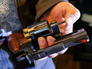 A man uses the ejection rod to eject the spent casings from ammunition fired from a revolver.