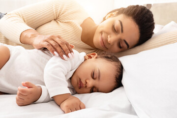 Loving Black Mom Hugging Sleeping Baby Lying In Bed In Bedroom At Home. Toddler Infant Sleeps Near Mom. Motherhood Lifestyle, Daytime Sleep Routine Concept. Selective Focus