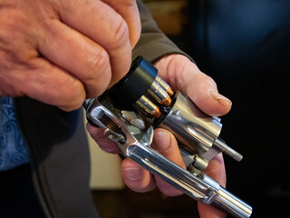 A man uses a speed loader to quickly reload bullets in a revolver.