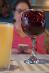 Glass of sangria with woman using smartphone in restaurant