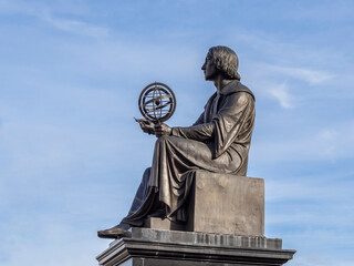 Nicolaus Copernicus with his model of the Solar System in Warsaw. Side view, blue sky.
