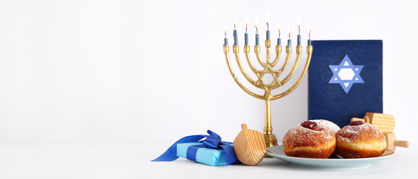 Menorah with dreidels, gift box, tasty donuts and Torah isolated on white background. Hanukkah celebration
