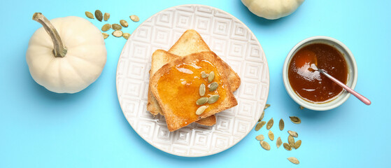 Plate of toasts with sweet pumpkin jam and seeds on blue background