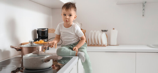 Little boy near electric stove in kitchen. Child at risk
