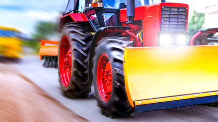 Red bulldozer tractor in soft focus with motion blur effect rushes along the highway with blade for...