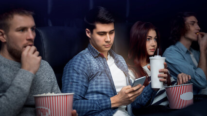 On movie night. Young man using mobile phone while watching film in cinema