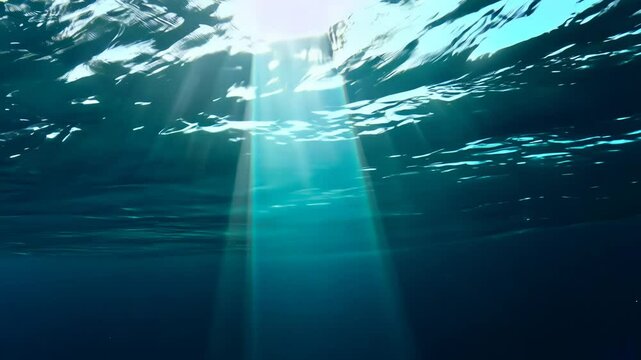 An ethereal aquatic world unfolds as sunlight slices through pristine turquoise seas. Radiant beams cast magical glow, descending beneath soft surface undulations into deeper water expanses.
