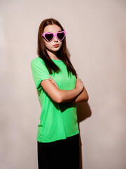 A young slim teenager girl in irish green shirt and black trousers is wearing heart shape party...