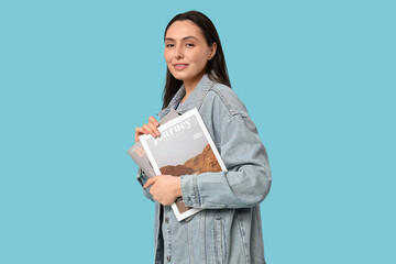 Fototapeta premium Beautiful young happy woman in stylish denim jacket with magazines on blue background