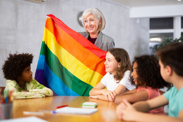 Qualified primary school teacher working in a high school tells pupils the Jewish Autonomous Region in class and holds the .national flag of the country in her hands